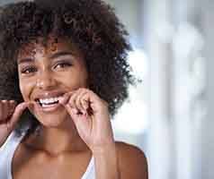 Woman smiling while flossing her teeth